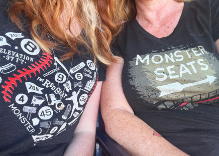 woman wearing Monster Seats-The Red Seat Design with the words Monster Seats painted on a wall fenway park boston women's black t-shirt