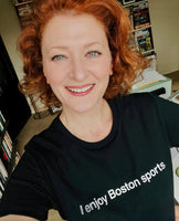 photo of a woman wearing black unisex t-shirt with the words i enjoy boston sports in white text