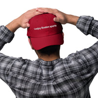 man wearing red baseball cap with "i enjoy boston sports" embroidered in white helvetica font