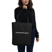 photo of woman holding black tote bag with the words "i enjoy boston sports" written in white helvetica font