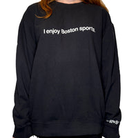woman wearing black unisex crewneck sweatshirt with the words i enjoy boston sports in white on the front