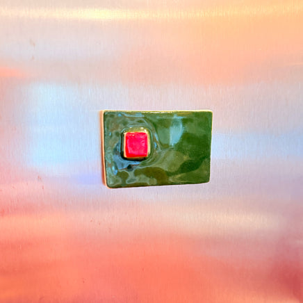 Green square magnet with a red center on a stainless steel refrigerator