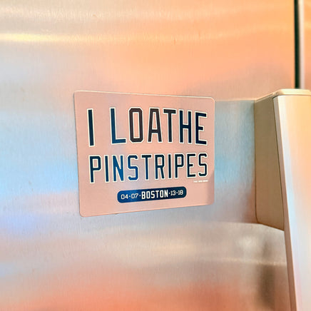Refrigerator magnet with text 'I LOATHE PINSTRIPES' on a stainless steel fridge