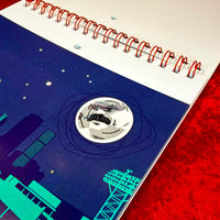 April 2027 artwork from The Red Seat calendar: a mustached moon over the Boston skyline and a Fenway light tower at night