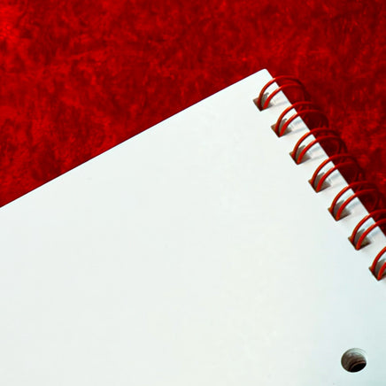 Close-up of the red spiral binding and hanging hole on The Red Seat 2027 wall calendar
