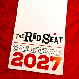 The Red Seat 2027 wall calendar cover with bold red 2027 lettering, shown on red velvet