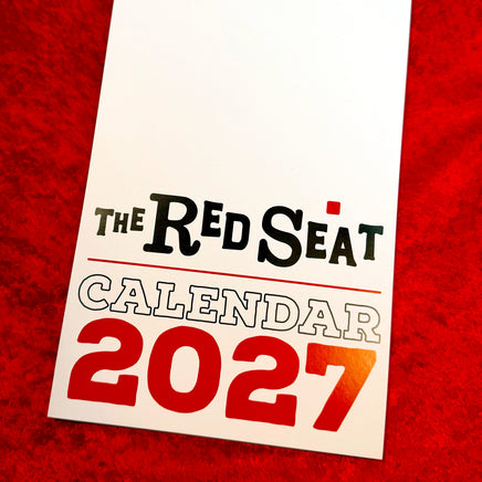 The Red Seat 2027 wall calendar cover with bold red 2027 lettering, shown on red velvet