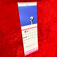 The Red Seat 2027 Red Sox wall calendar hanging open to February, with Yaz statue art, pink date grid, and a hidden QR code