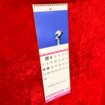 The Red Seat 2027 Red Sox wall calendar hanging open to February, with Yaz statue art, pink date grid, and a hidden QR code