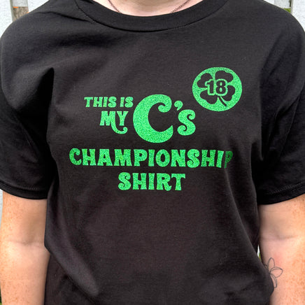 person wearing Black unisex t-shirt with the words this is my C's championship shirt in glittery green lettering