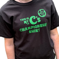 person wearing Black unisex t-shirt with the words this is my C's championship shirt in glittery green lettering