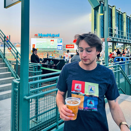 Photo of a man at fenway park wearing Navy blue unisex t-shirt with boston citgo sign design in colorful 4 up grid in the style of andy warhol