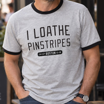 Man wearing heather gray I Loathe Pinstripes Red Sox ringer tee with black trim and jeans outside a Boston cafe