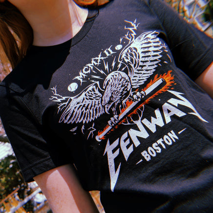 woman wearing Black unisex t-shirt featuring a heavy metal-style graphic of a screaming eagle with spread wings gripping a flaming baseball bat, with the word "FENWAY" in Metallica-inspired lettering, "BOSTON" below, and "MCMXII" in Roman numerals above — The Red Seat original design