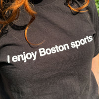 closeup photo of a woman wearing black unisex t-shirt with the words i enjoy boston sports in white text
