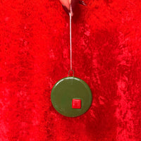 Green circular ornament with a red square on a red textured background