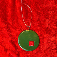 Green circular ornament with a red square on a red textured background