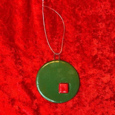 Green circular ornament with a red square on a red textured background