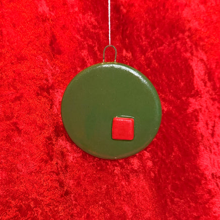 Green circular ornament with a red square on a red textured background