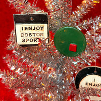 Decorative Christmas ornaments from The Red Seat on a tinsel tree with a red background