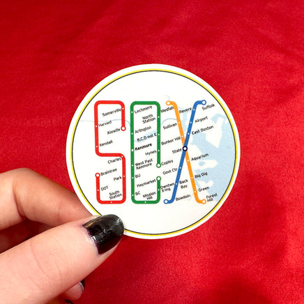 person holding 2" round sticker of design of the boston MBTA map in the shape of the word SOX