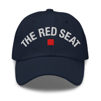 Front view of navy dad cap with “The Red Seat” embroidered in white and red icon