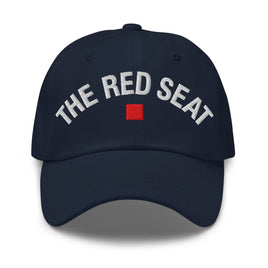 Front view of navy dad cap with “The Red Seat” embroidered in white and red icon