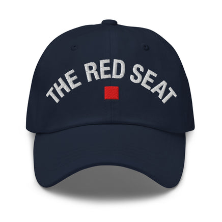 Front view of navy dad cap with “The Red Seat” embroidered in white and red icon