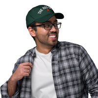 Man wearing a green cap with text, glasses, and plaid shirt on a white background