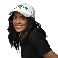 Woman wearing a white cap with 'The Red Seat' logo on a white background