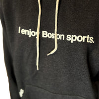 close up of black unisex hoodie with the words i enjoy boston sports in white with the red seat logo