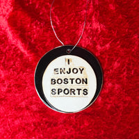 photo of round white and black porcelain ornament that says, i enjoy boston sports on red background