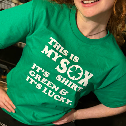 close up photo of woman wearing green unisex t-shirt from the red seat with white text that says "this is my sox shirt. it's green and it's lucky" on the front.