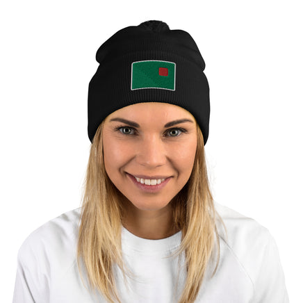 photo of a woman wearing black pom pom beanie with the red seat logo in green and red embroidered on the cuff
