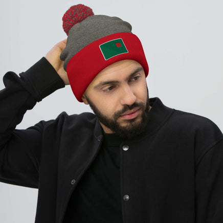 photo of a man wearing grey and red pom pom beanie with the red seat logo in green and red embroidered on the cuff