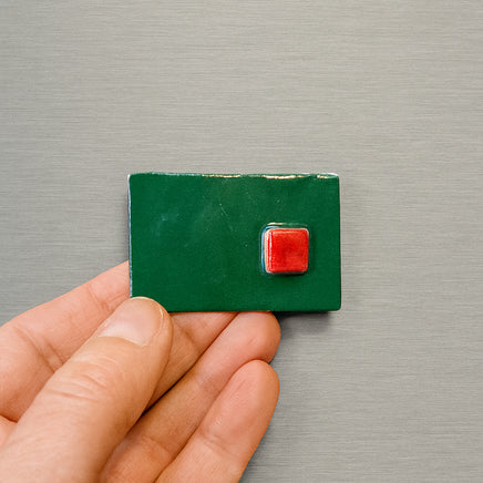 Green square handmade magnet with a red square on metallic surface