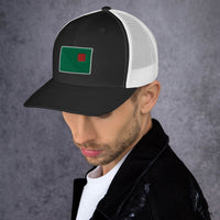 photograph of a man wearing a black trucker with white mesh with fenway park's red seat on a green background