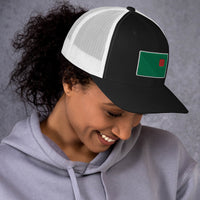 photograph of a woman wearing a black trucker with white mesh with fenway park's red seat on a green background
