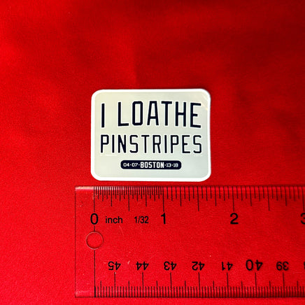 photo of small waterproof vinyl sticker of I Loathe Pinstripes-The Red Seat grey design with boston world series wins Yankees Suck with a ruler on red background