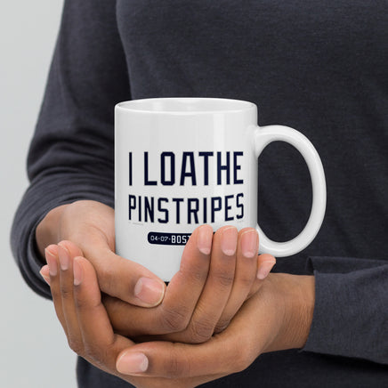person holding 11 oz white ceramic mug with the words i loathe pinstripes in new york yankees lettering navy blue text and boston red sox world series wins